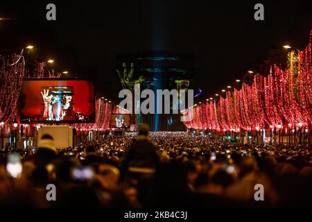 People gather near the illuminated Arc de Triomphe on the Champs-Elysees for New Year's celebrations in the French capital Paris on December 31, 2018. A fireworks display and sound and light show under the theme 'fraternity' is set to go ahead on the Champs-Elysees despite plans for further 'yellow vest' anti-government protests at the famed avenue. (Photo by Sameer Al-Doumy/NurPhoto) Stock Photo