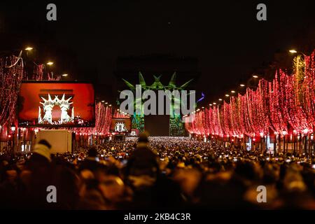 People gather near the illuminated Arc de Triomphe on the Champs-Elysees for New Year's celebrations in the French capital Paris on December 31, 2018. A fireworks display and sound and light show under the theme 'fraternity' is set to go ahead on the Champs-Elysees despite plans for further 'yellow vest' anti-government protests at the famed avenue. (Photo by Sameer Al-Doumy/NurPhoto) Stock Photo