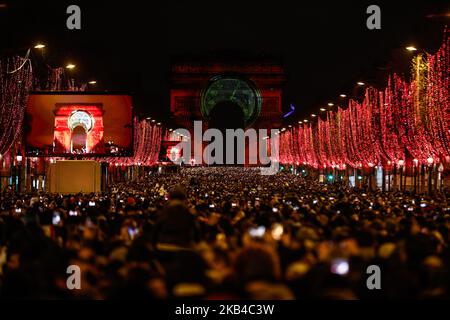 People gather near the illuminated Arc de Triomphe on the Champs-Elysees for New Year's celebrations in the French capital Paris on December 31, 2018. A fireworks display and sound and light show under the theme 'fraternity' is set to go ahead on the Champs-Elysees despite plans for further 'yellow vest' anti-government protests at the famed avenue. (Photo by Sameer Al-Doumy/NurPhoto) Stock Photo