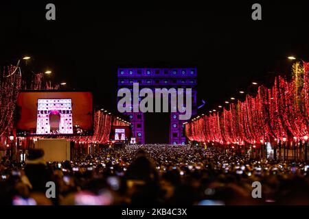 People gather near the illuminated Arc de Triomphe on the Champs-Elysees for New Year's celebrations in the French capital Paris on December 31, 2018. A fireworks display and sound and light show under the theme 'fraternity' is set to go ahead on the Champs-Elysees despite plans for further 'yellow vest' anti-government protests at the famed avenue. (Photo by Sameer Al-Doumy/NurPhoto) Stock Photo