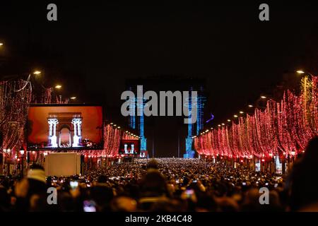 People gather near the illuminated Arc de Triomphe on the Champs-Elysees for New Year's celebrations in the French capital Paris on December 31, 2018. A fireworks display and sound and light show under the theme 'fraternity' is set to go ahead on the Champs-Elysees despite plans for further 'yellow vest' anti-government protests at the famed avenue. (Photo by Sameer Al-Doumy/NurPhoto) Stock Photo