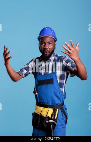 Violent and angry builder expressing anger and annoyance in the studio, having an argument in front of the camera. Unhappy and aggressive person shaking hands and feeling frustrated. Stock Photo