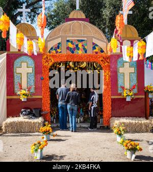 Visitors look in on an elaborate Dia de los Muertos (Day of the Dead) altar area, created from a cargo container. Stock Photo