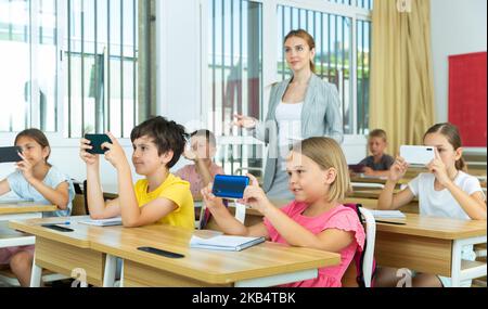 Pupils using mobile phones during lesson in school Stock Photo
