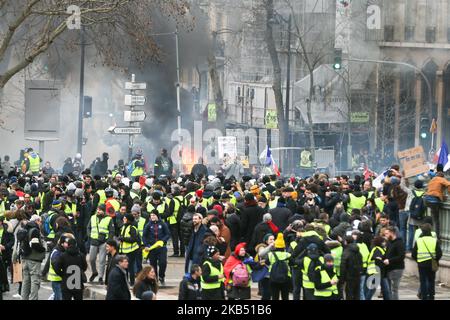 Protesters stand behind a burning barricade during an anti-government demonstration called by the 'yellow vests' (gilets jaunes) movement near the Place de la Bastille in Paris on January 26, 2019. 'Yellow vest' anti-government protesters have taken to the streets in France for the 11th consecutive Saturday on January 26, despite recent divisions in their ranks, and with a displayed tenacity facing an executive which is regaining popularity ten days after the opening of the 'great national debate', the French president's bid to prove he will take on board the fierce criticism of 'yellow vest'  Stock Photo