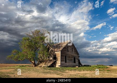 An old, abandoned house with dark storm clouds in rural Nebraska Stock Photo