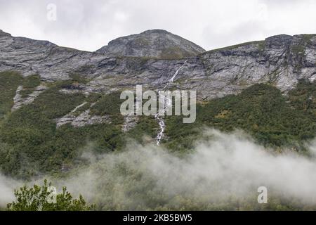 Beautiful waterfalls inside intense nature in dramatic scenery with clouds or green forest natural environment, seen at the fjords in Norway with forests and steep mountains. Water coming from high altitude mountain peaks and glaciers ending up throughValldola river to the fjords and the sea at the area of Valldal and Valldalen valley on 31 August 2019. (Photo by Nicolas Economou/NurPhoto) Stock Photo