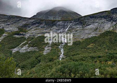 Beautiful waterfalls inside intense nature in dramatic scenery with clouds or green forest natural environment, seen at the fjords in Norway with forests and steep mountains. Water coming from high altitude mountain peaks and glaciers ending up throughValldola river to the fjords and the sea at the area of Valldal and Valldalen valley on 31 August 2019. (Photo by Nicolas Economou/NurPhoto) Stock Photo