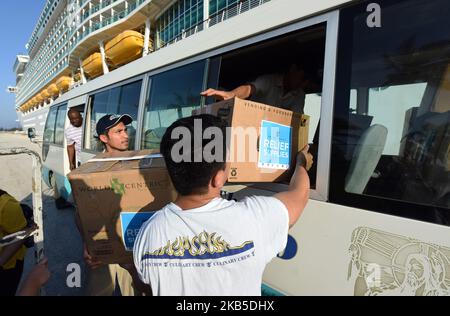 Crew members of Royal Caribbean International's Mariner of the Seas load cases of drinking water and prepared meals for Hurricane Dorian victims into a church bus on September 7, 2019 in Freeport, Bahamas. The ship is also providing an estimated 300 Freeport evacuees of the storm with food, water, an opportunity to take a shower, as well as transportation to Nassau, New Providence. (Photo by Paul Hennessy/NurPhoto) Stock Photo