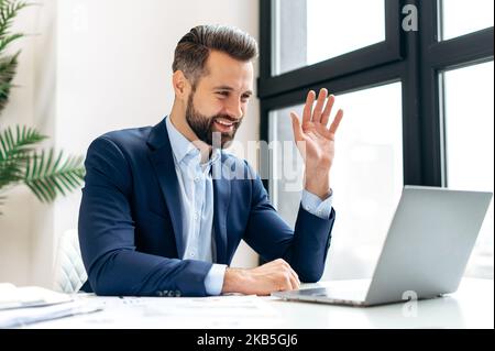 Positive caucasian businessman, executive manager, looking at laptop screen and talking by video conference, having online virtual meeting with colleagues, smiling. Online video communication Stock Photo