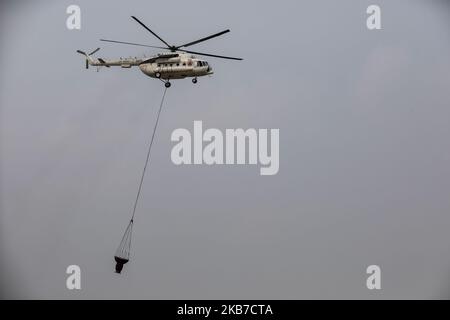 National Disaster Management Agency (BNPB) s Mi-8MSB-T water bombing helicopter carries a water container after taking off from the Tjilik Riwut airport in Palangka Raya, Central Kalimantan province, Indonesia, October 1, 2019. Firefighters, military personnel and water-dropping helicopters have been deployed to combat the fires in Sumatra and Borneo that have caused thick haze in the neighboring countries, Singapore and Malaysia. (Photo by Andrew Gal/NurPhoto) Stock Photo