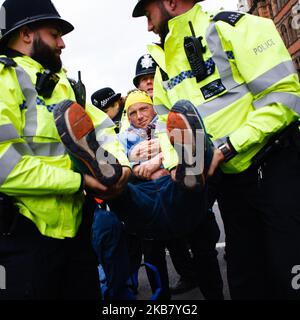 A members of climate change activist group Extinction Rebellion (XR) is arrested by police on Whitehall on the second day of the group's 'International Rebellion' in London, England, on October 8, 2019. By early Tuesday evening the Metropolitan Police were reporting that a total of 531 arrests had been made over the two days of protests in the city so far, with police officers working to clear people and tents from many of the sites taken over by activists yesterday. Similar blockades by Extinction Rebellion in April, at sites including Oxford Circus and Waterloo Bridge, saw more than 1,000 ar Stock Photo