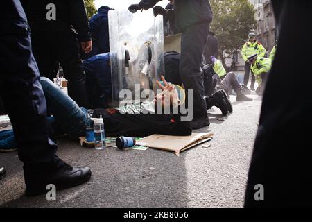 A member of climate change activist movement Extinction Rebellion (XR) gestures as police officers use power tools to separate him from another demonstrator on Whitehall on the third day of the group's 'International Rebellion' in London, England, on October 9, 2019. Police officers today continued to clear demonstrators and tents from sites across Westminster, with activists having been warned yesterday that they must move to a designated protest area around Nelson's Column in Trafalgar Square or face arrest. Similar blockades by Extinction Rebellion in April, at sites including Oxford Circus Stock Photo