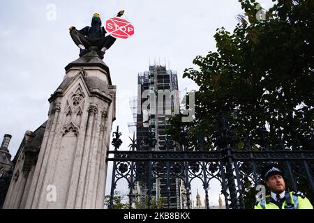 A member of climate change activist movement Extinction Rebellion (XR), wearing a gas mask and surrounded by police, demonstrates on top of the wall of the Parliamentary Estate in London, England, on October 15, 2019. XR has vowed to continue its two-week 'rebellion' in the city despite the Metropolitan Police last night issuing a ban on protest actions by the group, and clearing away its encampment in Trafalgar Square. (Photo by David Cliff/NurPhoto) Stock Photo
