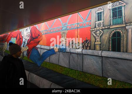 A visitor walks by a mural ‘Der Mauerspringer’, (‘The Wall Jumper’), painted by Gabriel Heimler, a part of a still-standing section of the former Berlin Wall called the East Side Gallery, on the eve of the upcoming 30th anniversary of the fall of the Berlin Wall. Germany marks three decades since the fall of the Berlin Wall this week with main celebrations in the German capital on Saturday, November 9, 2019. On Friday, November 8, 2019, in Berlin, Germany. (Photo by Artur Widak/NurPhoto) Stock Photo