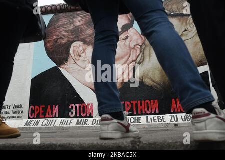 Visitors seen near a mural by Russian artist Dmitri Vrubel ‘My God, Help Me to Survive This Deadly Love’, commonly known as ‘Fraternal Kiss’ that shows former Soviet Union leader Leonid Brezhnev kissing former east German leader Erich Honecker at a still-standing section of the former Berlin Wall called the East Side Gallery, seen on the eve of the upcoming 30th anniversary of the fall of the Berlin Wall. On Friday, November 8, 2019, in Berlin, Germany. (Photo by Artur Widak/NurPhoto) Stock Photo