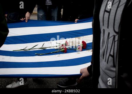 Students wear a blood-stained Greek flag with roses, which was in the National Technical University in Athens, Greece on November 17, 2019 during a demonstration on the 46th anniversary of Polytechnic school, uprising against the military Junta that was ruling Greece in 1993. (Photo by Nikolas Kokovlis/NurPhoto) Stock Photo