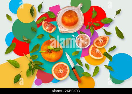 Grapefruit ripe fresh whole, slices and juice on colorful background with green leaves scattered on table. Top view. Stock Photo