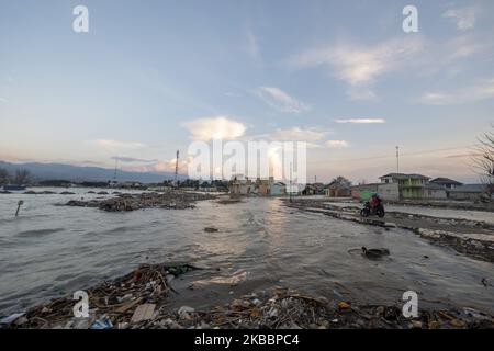 Motorbike riders will break the tidal flood in Kampung Lere, Palu, Central Sulawesi, Indonesia, on November 27, 2019. The high tide caused residents' houses in the area to be flooded. The condition was exacerbated by land subsidence as high as 1.5 meters due to the earthquake on 28 September 2018 then. (Photo by Basri Marzuki/NurPhoto) Stock Photo