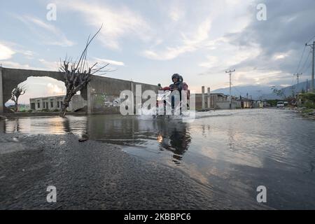 Motorbike riders break into a flood of tidal flooding in Kampung Lere, Palu, Central Sulawesi, Indonesia, on November 27, 2019. The high tide caused residents' houses in the area to be flooded. The condition was exacerbated by land subsidence as high as 1.5 meters due to the earthquake on 28 September 2018 then. (Photo by Basri Marzuki/NurPhoto) Stock Photo
