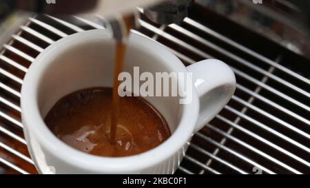 Beauatiful extreme macro close up view of an espresso shot or pour into a small white espresso tulip shaped cup. Barista making the perfect coffee sho Stock Photo
