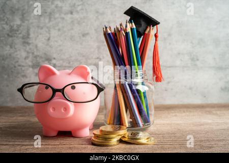 Pigging bank wearing eyeglass with colorful pencils; saving bank education concept. Stock Photo