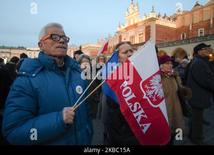 A man holds EU and Polish flags during another solidarity with harrassed judges protest In Krakow's Main Martket Square. A few hundreds people, mainly members of Krakow's Committee for the Defence of Democracy (Polish: KOD) and their supporters, joined this evening other protesters accross the country to express their solidarity with judges during 'We Do It For Everyone - Solidarity With Judges!' protest. On Sunday, December 1, 2019, in Krakow, Poland. (Photo by Artur Widak/NurPhoto) Stock Photo