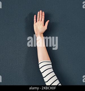 I would like to make a suggestion. Studio shot of an unrecognizable woman raising her hand against a grey background. Stock Photo