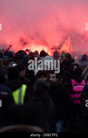 Looking at the whole and from above, the procession of yellow vest activists and independents dressed in black with demonstrators walking behind a large banner that reads 'Public, Private, all together until withdrawal' and in the middle of the red smoke on Thursday, December 12, 2019, the day after the Prime Minister's announcements on pension reform and on the eighth day of the strike against reform, the unions called for a third day of demonstration to express their refusal. A few thousand people answered the call, mainly railway workers from SNCF and RATP, professors, students and CGT trad Stock Photo