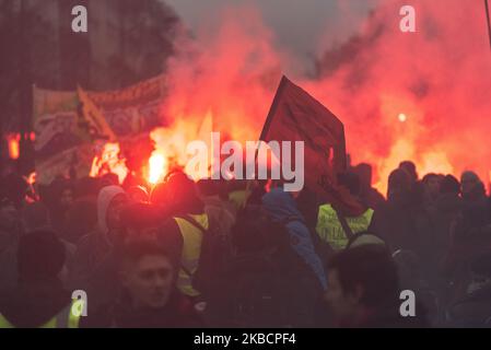 Looking at the whole and from above, the procession of yellow vest activists and independents dressed in black with demonstrators walking behind a large banner that reads 'Public, Private, all together until withdrawal' and in the middle of the red smoke on Thursday, December 12, 2019, the day after the Prime Minister's announcements on pension reform and on the eighth day of the strike against reform, the unions called for a third day of demonstration to express their refusal. A few thousand people answered the call, mainly railway workers from SNCF and RATP, professors, students and CGT trad Stock Photo