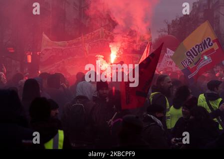 Looking at the whole and from above, the procession of yellow vest activists and independents dressed in black with demonstrators walking behind a large banner that reads 'Public, Private, all together until withdrawal' and in the middle of the red smoke on Thursday, December 12, 2019, the day after the Prime Minister's announcements on pension reform and on the eighth day of the strike against reform, the unions called for a third day of demonstration to express their refusal. A few thousand people answered the call, mainly railway workers from SNCF and RATP, professors, students and CGT trad Stock Photo