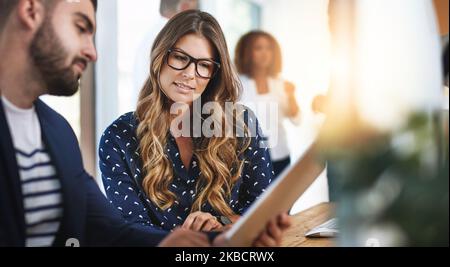 Sharing digital ideas. colleagues working together on a digital tablet in an office. Stock Photo