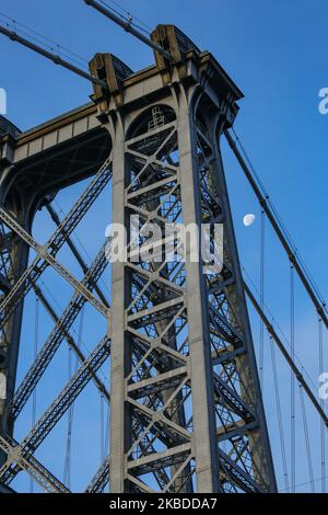 The moon through Williamsburg Bridge, a suspension bridge in New York City across the East River, connecting the Lower East Manhattan with Williamsburg neighborhood in Brooklyn, at Broadway. The illuminating Luna, earth's natural satellite in orbit, as seen at the Waning gibbous, lunar calendar phase, with 76% visible. NYC, USA - November 17, 2019 (Photo by Nicolas Economou/NurPhoto) Stock Photo