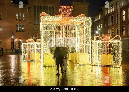 Gift box xmas art installation. Christmas Decoration in the city center of Amsterdam in The Netherlands with thousands of tourists and visitors going shopping, walking in the streets with bags and taking pictures with the illuminated traditional buildings and festive installations. December 19, 2019 - Amsterdam, Netherlands (Photo by Nicolas Economou/NurPhoto) Stock Photo