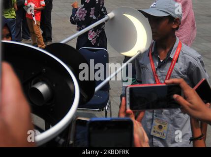 Visitors observe the phenomenon of a partial solar eclipse (GMP) through a telescope at Planetarium, Taman Ismail Marzuki (TIM), Cikini, Jakarta, on December, 26,2019. Information from the Meteorology, Climatology and Geophysics Agency (BMKG), solar eclipses in Jakarta were seen around 70 percent, the phenomenon occurred until 12.36 waktu Indonesia Barat. (Photo by Dasril Roszandi/NurPhoto) Stock Photo