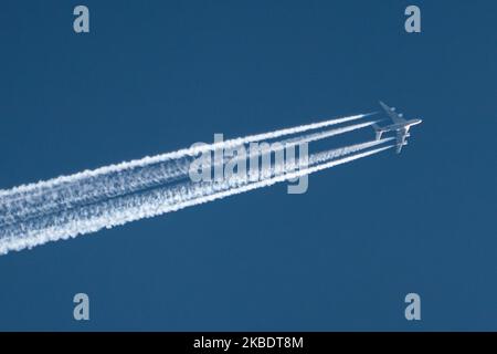 An airline commercial aircraft overflying in the blue sky long contrails of condensation behind it at very high altitude of 40.000 feet. The airliner is an Etihad Airways wide-body, long haul double-decker Airbus A380 airplane with registration A6-APC flying from Abu Dhabi, United Arab Emirates AUH to London Heathrow LHR airport in England, UK. ETIHAD logo is visible on the belly of the fuselage of the jetliner The overfly plane is above Maastricht city in The Netherlands, coming from Germany and entering the airspace of Belgium in a few minutes. (Photo by Nicolas Economou/NurPhoto) Stock Photo