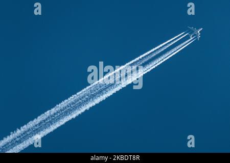 An airline commercial aircraft overflying in the blue sky long contrails of condensation behind it at very high altitude of 40.000 feet. The airliner is an Etihad Airways wide-body, long haul double-decker Airbus A380 airplane with registration A6-APC flying from Abu Dhabi, United Arab Emirates AUH to London Heathrow LHR airport in England, UK. ETIHAD logo is visible on the belly of the fuselage of the jetliner The overfly plane is above Maastricht city in The Netherlands, coming from Germany and entering the airspace of Belgium in a few minutes. (Photo by Nicolas Economou/NurPhoto) Stock Photo