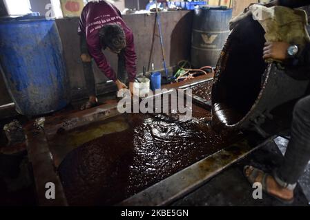 Workers pours Molten Raw Hardened molasses on mud bucket to prepare molasses “Chaku” at Tokha, Kathmandu, Nepal on January 10, 2020. Molasses “Chaku” is usually prepared and consumed during the Maghe Sankranti Festival and throughout winter by Nepalese. It is believed that consuming “Chaku” promotes good health and warmth in the cold months. In the market shopkeeper sells 250 grams of Chaku at NRs 40 to 50, depending on the ingredients used. (Photo by Narayan Maharjan/NurPhoto) Stock Photo