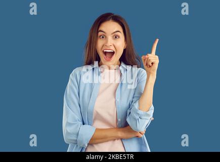 Woman has good idea, points up and looks at camera with happy excited face expression Stock Photo