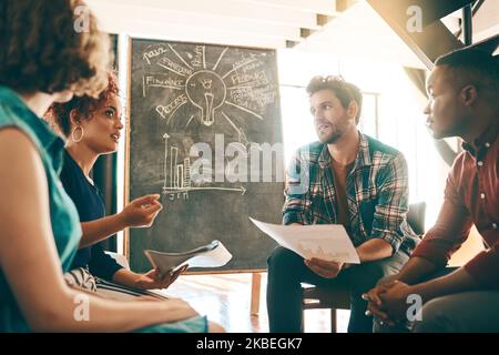 Discussing how to go about their new project. a group of designers having a discussion in an office. Stock Photo