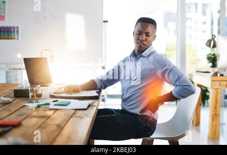 I think I need a little break. a young businessman suffering from back pains while trying to work in the office. Stock Photo
