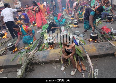 A girl sits on a road divider as devotees cook sweet dishes during a Hindu religious festival of ‘Pongal’ in Mumbai, India on 15 January 2020. Pongal is celebrated to convey gratitude to the Sun God for a good harvest. (Photo by Himanshu Bhatt/NurPhoto) Stock Photo