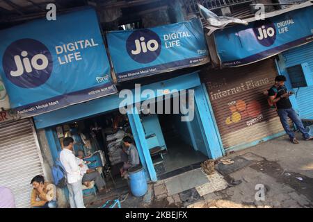 People stand in front of a shop with an advertisement of Reliance Jio Infocomm Ltd in Mumbai, India on 15 January 2020. (Photo by Himanshu Bhatt/NurPhoto) Stock Photo