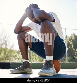 Depression, sport and man on basketball court for fitness outdoors. Stressed black athlete, mental health and tired after wellness workout or exercise Stock Photo