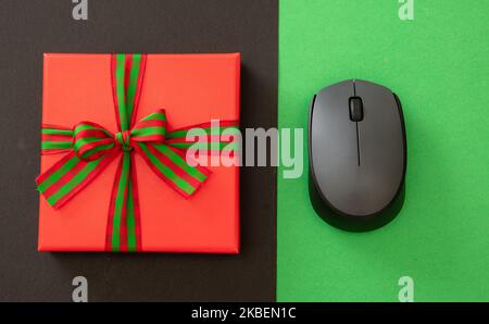 Cyber Monday and Black Friday Sale. Red Gift box with ribbon bow and computer mouse on green and black background, top view Stock Photo