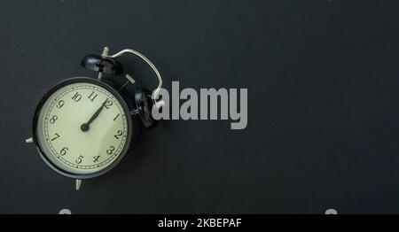Black retro alarm clock on dark background top view, copy space. Black Friday Sale time concept. Stock Photo