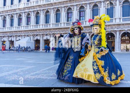 Venice, Italy - March 01, 2022: Couple dressed in traditional costumes stand in front of the Ducal palace, part of the Venice Mask Carnival, Veneto, I Stock Photo