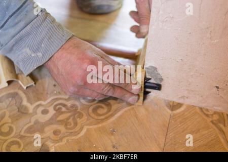young worker in uniform installing new baseboard at home Stock Photo