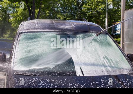 washing car windshield in car washes with high pressure water with foam Stock Photo