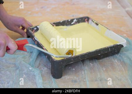 painting the apartment with yellow paint tray and roller tool Stock Photo
